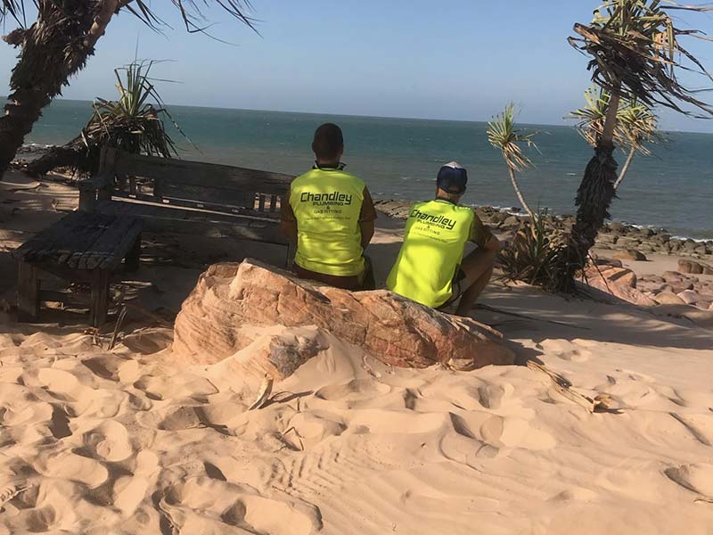Chandley Plumbing team members sitting on beach